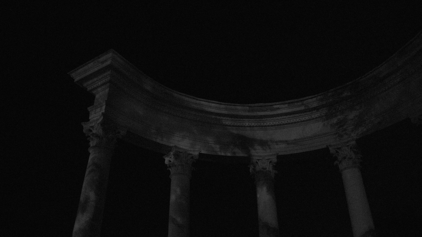 Ancient Roman pillars standing against a dark night sky